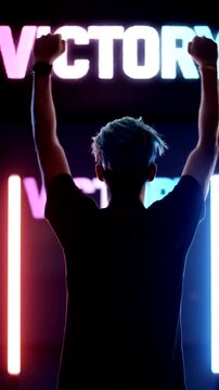 A person stands triumphantly with raised arms in front of an illuminated sign celebrating victory and success.