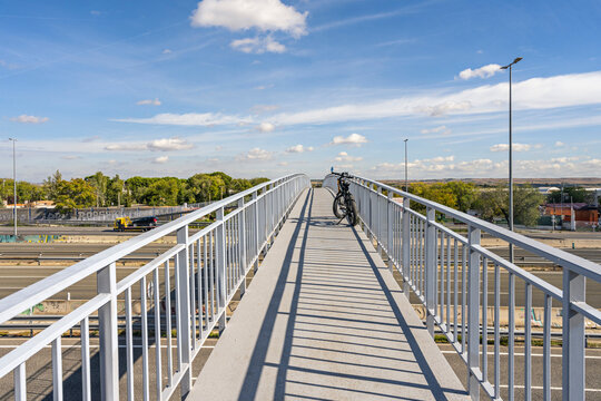 A front view capturing the elegance of the white metal pedestrian overpass extending in a gentle curve over the highway