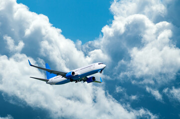 Airplane in the flight, travel background with airplane flying in the blue sky high above the ground