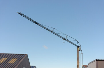 industrial tower crane stands out against a clear blue sky in an industrial area