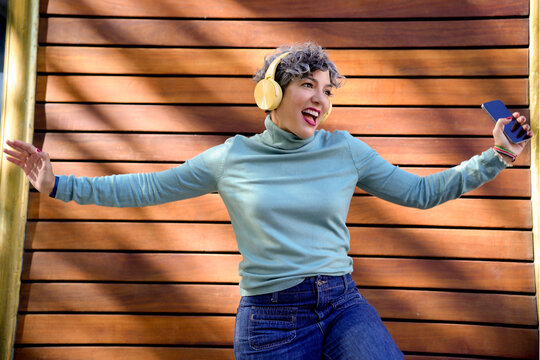 Joyful tech woman enjoying music in headphones
