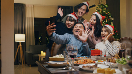 Group of Asia colleague gathering New year holidays party together. Happy friend group mobile phone...