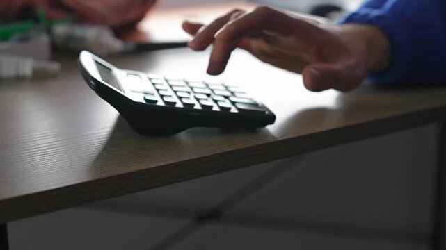 Working in a bank and using a calculator to calculate profits.
A businessman with a calculator doing mathematical calculations.
An adding machine on a banker's desk.