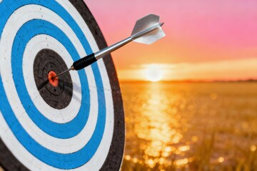 Target with dart at sunset over water, symbolizing focus and goals.