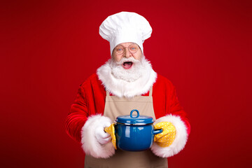 Santa chef in white hat and apron holding blue pot in a festive kitchen style scene against a bold red background smiling warmly for Christmas