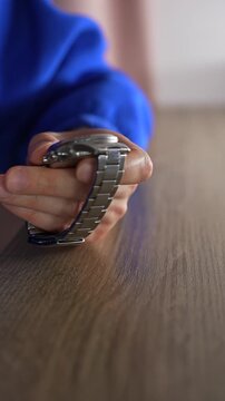 A man in a blue sweater holds a metal wristwatch with a metal strap.
The man is checking the functionality of his watch.
Watch, time, accessory, luxury, hour, minutes