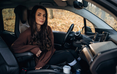 Looking at the camera, feeling good. Beautiful woman is sitting in her electric car