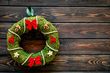Christmas wreath made of green moss with a red bows on the wall. New Year DIY decoration