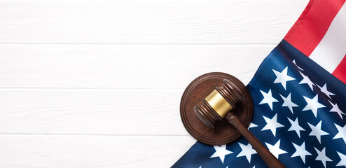 Judge gavel and American flag on a white wooden desk. Symbolizes justice and law enforcement.