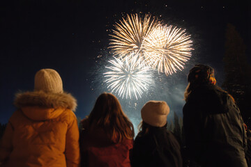 family gathers in their backyard lighting up night sky with colorful fireworks
