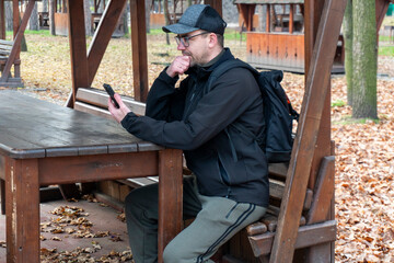 A young man sits at a table in a gazebo in a park