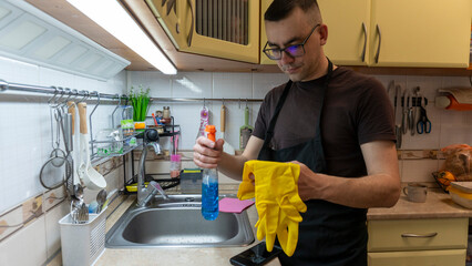 Cleaning process in the apartment. A young man cleans the kitchen
