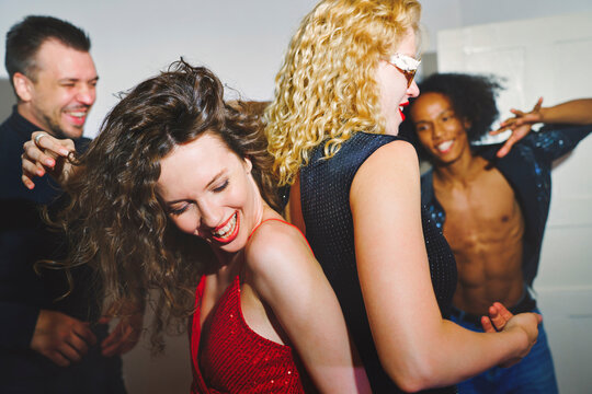 Friends dancing and laughing together at a fun home party