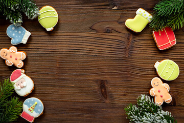 Flat lay of Christmas gingerbread cookies and New Year with fir branches on dark wooden background, top view. Greeting concept