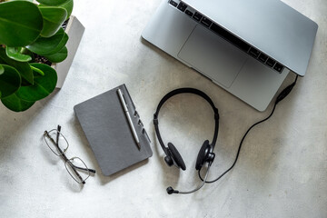 Headset and laptop - customer support equipment at call center, top view. Online conference work space. Online education concept