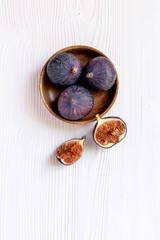Purple ripe figs in a wooden bowl top view on a wooden background