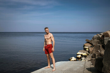 Young man on a wild beach with calm ocean view