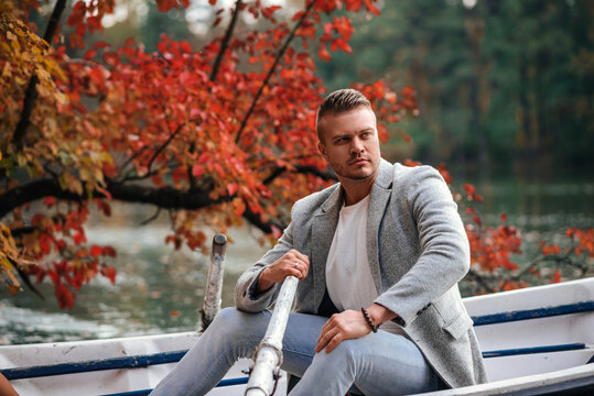 Man rowing boat in autumn park near a serene lake