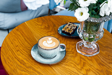 coffee latte art abd flowers on wood table in cafe outdoor nature light