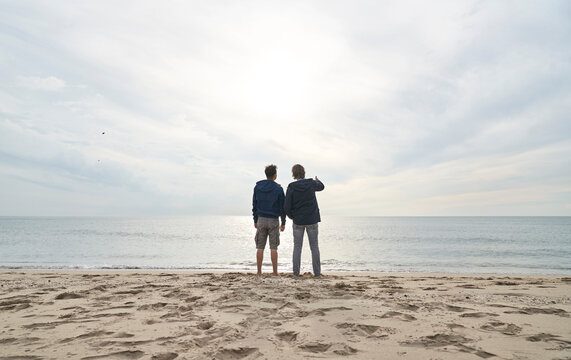Man standing with father in front of sea at beach
