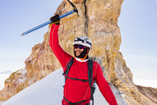 Hiker triumphantly holding ice axe on Iztaccihuatl summit