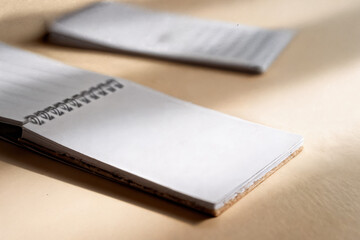 Close up shot of two spiral notebooks with blank pages on a neutral colored surface in soft lighting