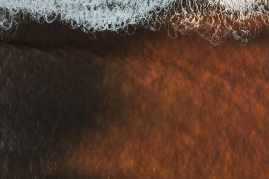 Top view of Asturias beach with frothy waves touching sand