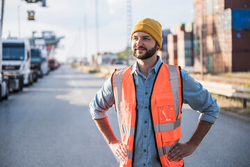 Thoughtful truck driver standing with hands on hip