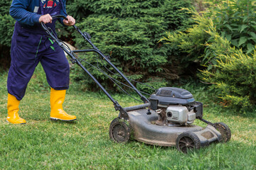 Gardening and country life. Banner. A man with a lawn mower is mowing the grass in the backyard. Agricultural equipment for garden maintenance.