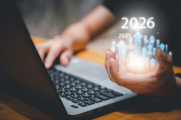 Businessman drawing digital growth arrows and bar graph with 2026 target. Futuristic concept for business goals, technology strategy, data-driven planning, success and innovation.