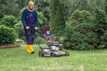 Gardening and country life. Banner. A man with a lawn mower is mowing the grass in the backyard. Agricultural equipment for garden maintenance.