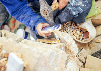 Skilled artisan using pliers to shape a piece of wood in a workshop, surrounded by various tools and materials, showcasing craftsmanship and dedication to the craft