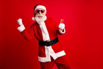Energetic Santa Claus Holding Smartphone Celebrating Christmas on a Red Background with Fun and...