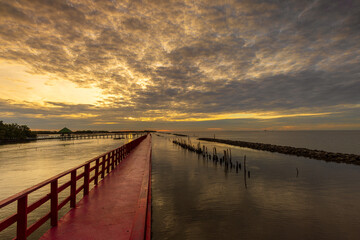 Obraz premium The red wooden bridge along the sea is a popular tourist attraction in Samut Sakhon Province, Thailand.