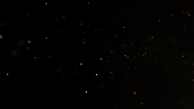 Super slow motion of small golden particles flying, isolated on black background. Filmed on high speed camera, 1000 fps