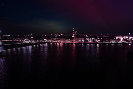 Riga Daugava riverfront at night shows magenta and violet aurora lights, Riga TV Tower beacons, and 11. novembra krastmala during Staro Riga 2025 and Independence Day - Powered by Adobe