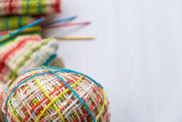 Colourful wool yarn placed beside knitted socks with clear copy space, showing vibrant fibres and...