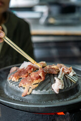 Close-up of Thai-style barbecue grill pan, known as Moo Kratha, with pork belly, shrimp, and vegetables cooking on a hot grill and soup. Popular Asian dining experience in Thailand.