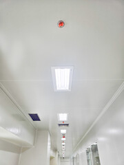 Perspective view of a white ceiling with lights and a fire alarm