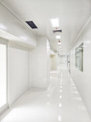 Long, white hallway with shiny floor and ceiling lights