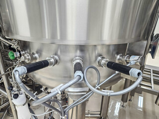 Obraz premium Close-up of a stainless steel industrial mixing tank with pipes and connections