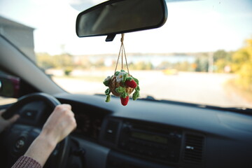 A dashboard hanger attached to the rearview mirror inside a small car.