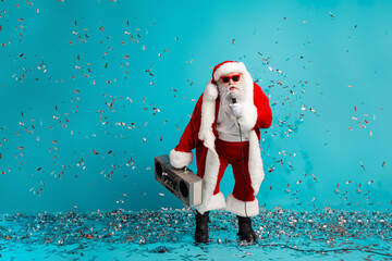 Santa performs with a boombox on a blue backdrop amid confetti celebrating Christmas with style and fun festive mood