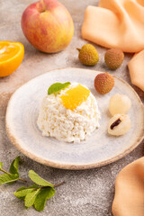 White Сottage cheese, Curd, with orange and lychee on brown concrete and orange textile, side view, close up.