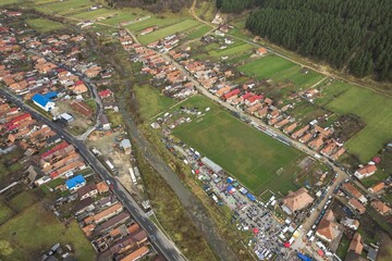 From above, Zarnesti showcases its scenic beauty with a bustling football field surrounded by lush greenery. Colorful houses dot the landscape, reflecting rural life in Romania