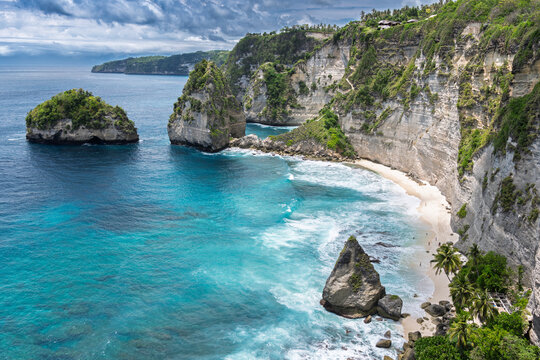 Nusa Penida, Indonesia – View of Diamond Beach with its turquoise water, white sand, and dramatic cliffs under bright tropical light.