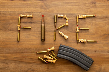 Close study of “FIRE” spelled from ammunition pieces with a magazine at the edge; the still...