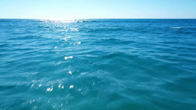 A stunning oceanic view with a clear blue sky, capturing the sunlight sparkling on the water
