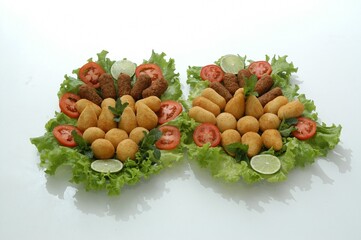 Flat lay of a Brazilian appetizer platter with fried snacks, lettuce, tomato, and lime. Perfect for food blogs, menus, or party planning content.
