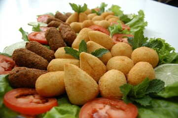 Flat lay of a Brazilian appetizer platter with fried snacks, lettuce, tomato, and lime. Perfect for food blogs, menus, or party planning content.